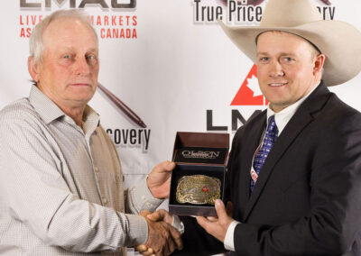 Champion Auctioneer, Casey Lawes, from the Provost Livestock Exchange in Provost Alberta is presented with the Canadian Limousin Association Buckle by Travis Hunter from the CLS.