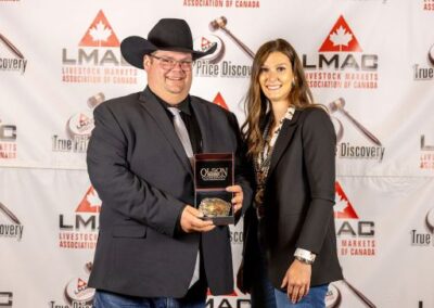 Canadian Shorthorn Association representative Shyla Chappell presents LMAC Champion Auctioneer Dave Jacob with the Champion Buckle.