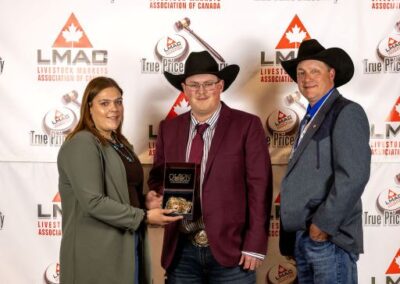 Man/Sask Champion Ty Cutler from Whitewood Livestock Sales receives the Championship buckle. Brie Bently from Boehringer Ingelheim presented the award. LMAC President Allan Munroe (r)