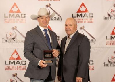 Reserve Champion Auctioneer Tyler Slawinski from the Gladstone and Ashern Auction Marts in Manitoba receives the Canadian Charolais Association Buckle from Charolais Representative John Meilhausen.